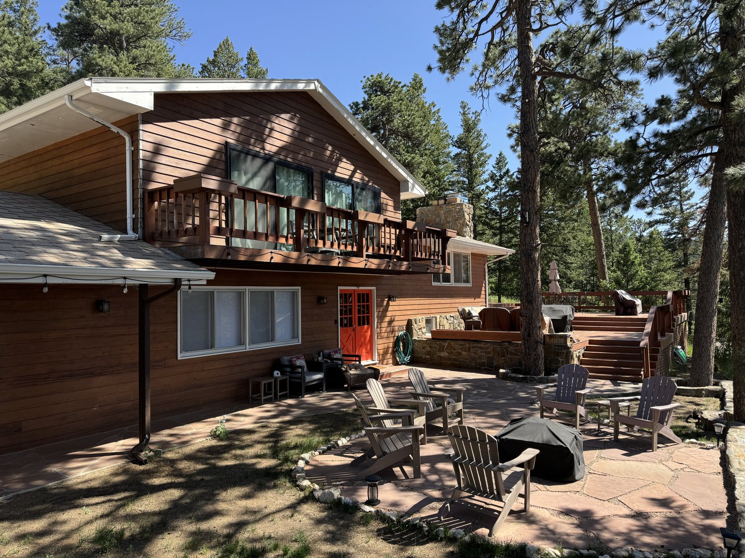 The house, upper deck, and flagstone patio with fire pit seating